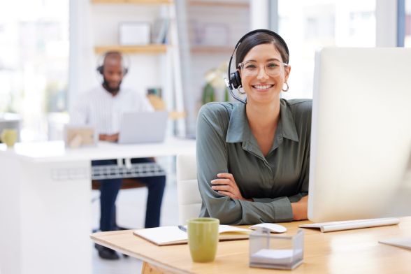 woman sitting behind a computer wearing a headset